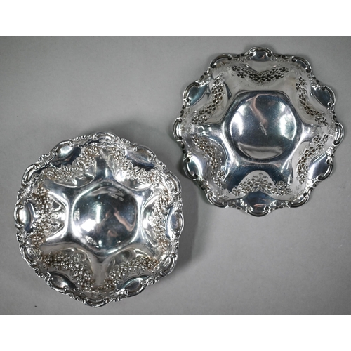 140 - An Edwardian pair of silver dishes with dimpled sides, scrolling rims and embossed and chased floral... 