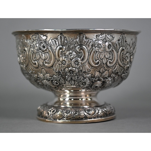 141 - An Edwardian silver rose bowl with embossed and chased floral and scroll decoration, on stemmed foot... 