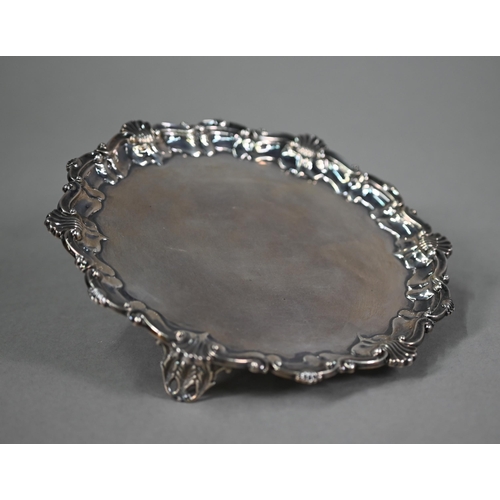 173 - An Edwardian circular silver card salver in the Georgian manner, with shell and scroll moulded borde... 