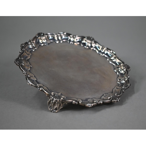 173 - An Edwardian circular silver card salver in the Georgian manner, with shell and scroll moulded borde... 