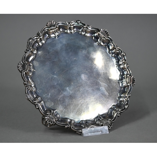 173 - An Edwardian circular silver card salver in the Georgian manner, with shell and scroll moulded borde... 