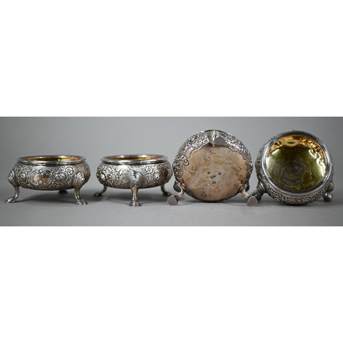 177 - A set of four George II silver circular salts with later floral embossed and chased decoration, on h... 