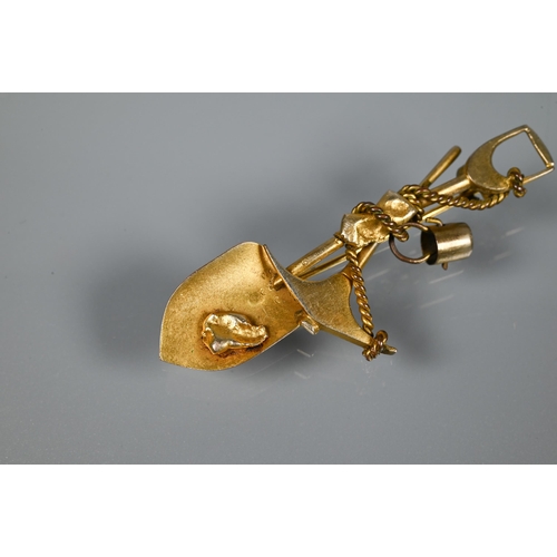 205 - A gold 'prospector' brooch, in the form of crossed spade and pickaxe, suspending a bucket and w... 