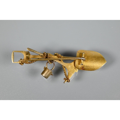 205 - A gold 'prospector' brooch, in the form of crossed spade and pickaxe, suspending a bucket and w... 