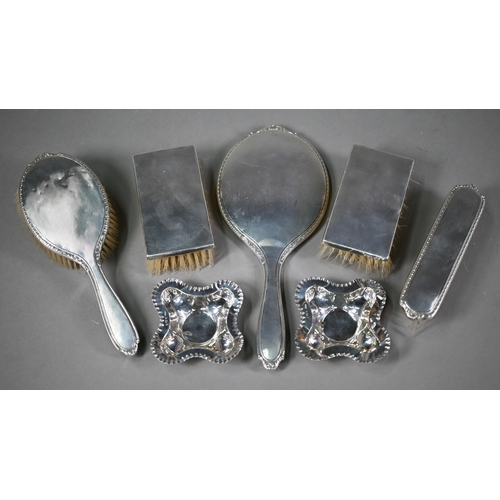 21 - Four engine-turned silver hairbrushes and a hand-mirror, Birmingham 1957, to/w two quatrefoil pin-di... 