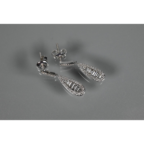 233 - A pair of modern 18ct white gold and diamond drop earrings, the tear drop baguette and brilliant cut... 