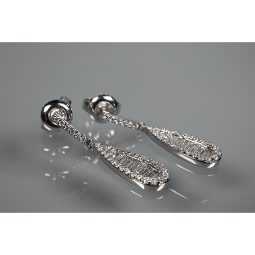 233 - A pair of modern 18ct white gold and diamond drop earrings, the tear drop baguette and brilliant cut... 