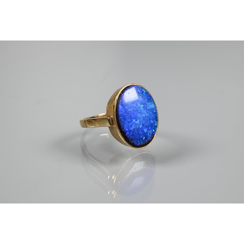 235 - An oval black opal doublet ring in yellow metal mount, size P