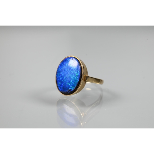 235 - An oval black opal doublet ring in yellow metal mount, size P