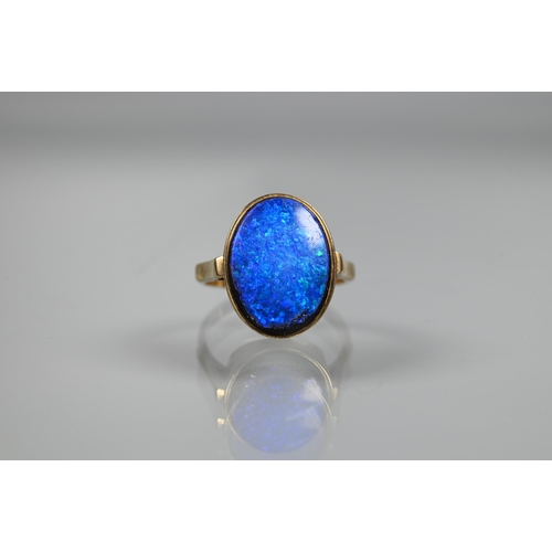 235 - An oval black opal doublet ring in yellow metal mount, size P