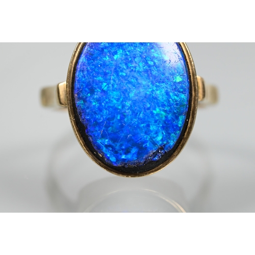 235 - An oval black opal doublet ring in yellow metal mount, size P