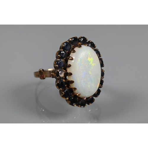 255 - An opal dress ring, the white oval opal surrounded by dark blue stones, yellow metal set, size Q, 2.... 