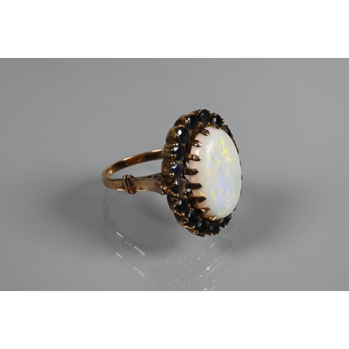 255 - An opal dress ring, the white oval opal surrounded by dark blue stones, yellow metal set, size Q, 2.... 