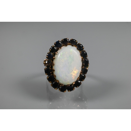 255 - An opal dress ring, the white oval opal surrounded by dark blue stones, yellow metal set, size Q, 2.... 