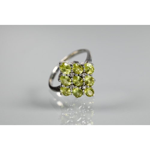 262 - A cluster ring comprising nine oval peridots, claw set with four diamonds between, white metal set s... 