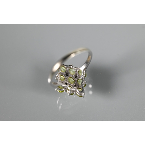 262 - A cluster ring comprising nine oval peridots, claw set with four diamonds between, white metal set s... 