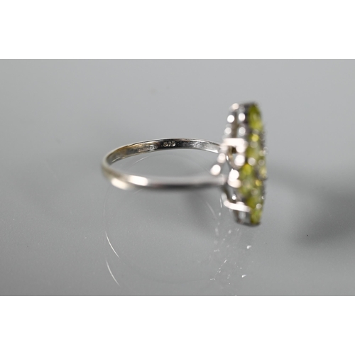 262 - A cluster ring comprising nine oval peridots, claw set with four diamonds between, white metal set s... 