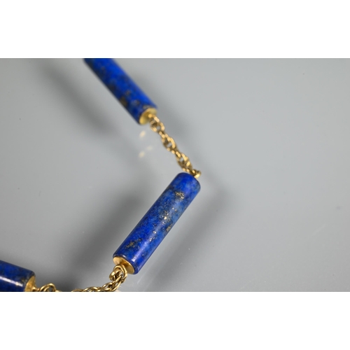 270 - A necklace formed of seven cylindrical lapis lazuli beads on yellow metal double link chain, stamped... 