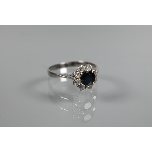 272 - A ring set circular blue sapphire surrounded by eight claw set brilliant cut diamonds, size P