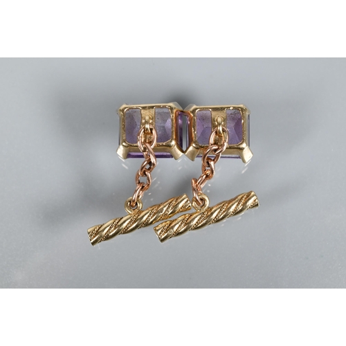 315 - A pair of chain-linked cufflinks set with rectangular amethyst with twisted baton backs, yellow meta... 