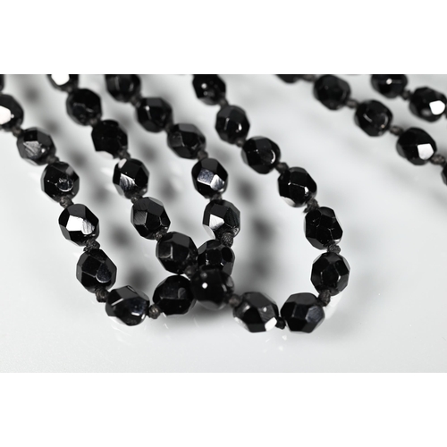 320 - A long black faceted bead necklace, double knotted throughout onto barrel clasp, 68 cm long (closed)