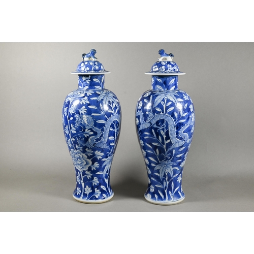 513 - A pair of 19th century Chinese blue and white vases with domed covers surmounted by guardian lion fi... 