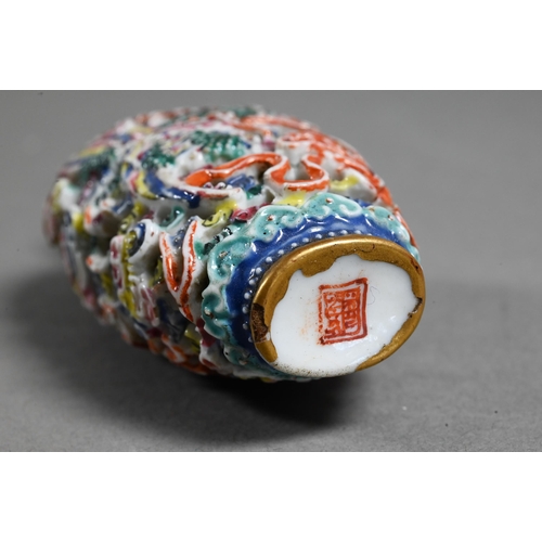 516 - A Chinese moulded porcelain famille rose snuff bottle with green glass stopper, modelled with a sinu... 