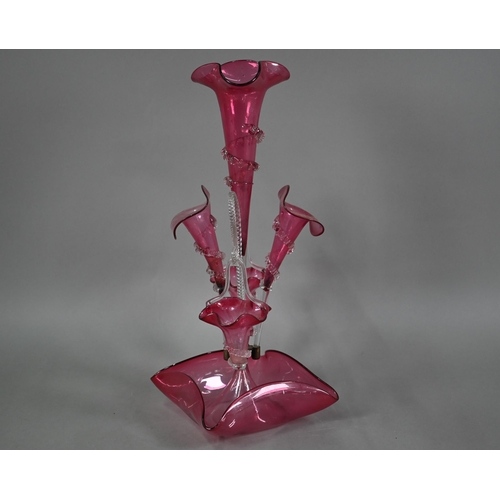 557 - A Victorian cranberry glass epergne with central flute vase flanked by two floral flutes and two bas... 