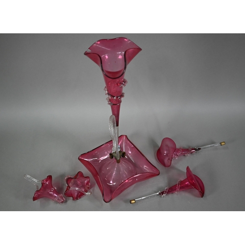 557 - A Victorian cranberry glass epergne with central flute vase flanked by two floral flutes and two bas... 