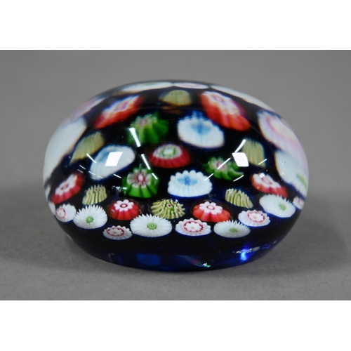 563 - A Clichy glass floral cane weight on a blue ground, 7.2 cm diam