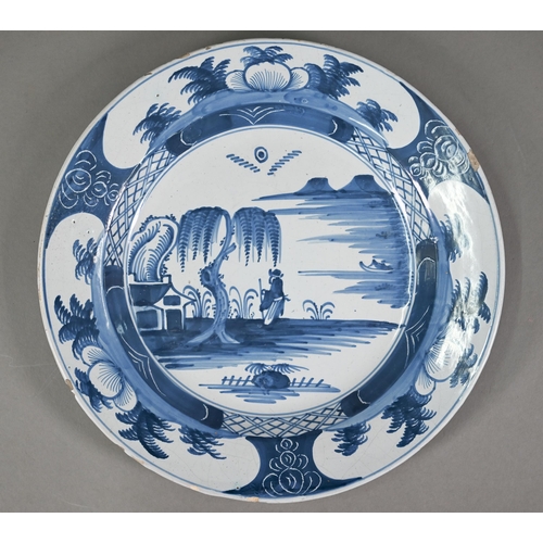 610 - A Delft blue and white plate, painted with chinoiserie coastal landscape within foliate reserves rim... 