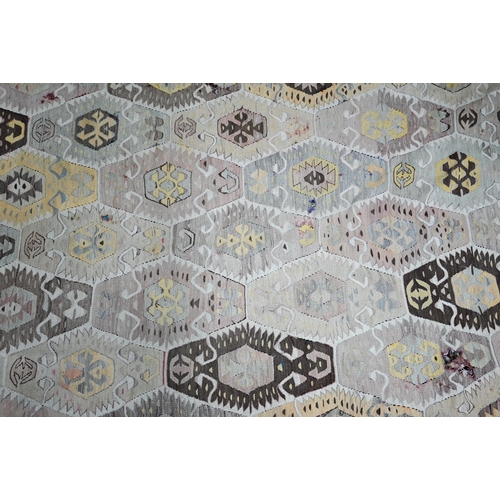 825 - An old Turkish kelim, the soft multi-coloured lozenge design on camel ground, 290 cm x 154 cm