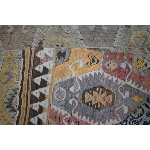 825 - An old Turkish kelim, the soft multi-coloured lozenge design on camel ground, 290 cm x 154 cm