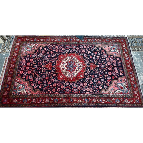 837 - A North West Persian Sarouk carpet, the red ground centred by a blue ground medallion and floral vin... 