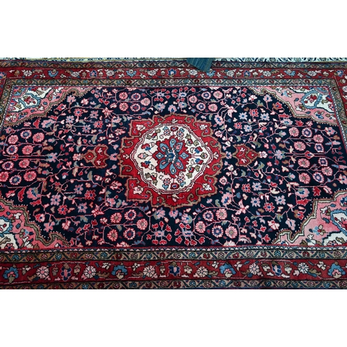 837 - A North West Persian Sarouk carpet, the red ground centred by a blue ground medallion and floral vin... 