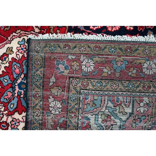 837 - A North West Persian Sarouk carpet, the red ground centred by a blue ground medallion and floral vin... 
