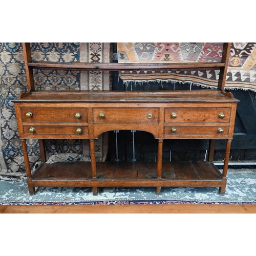 875 - An 18th century oak high dresser, the open back three tier rack with iron hooks, over an arrangement... 