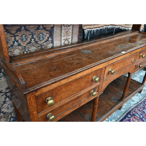 875 - An 18th century oak high dresser, the open back three tier rack with iron hooks, over an arrangement... 