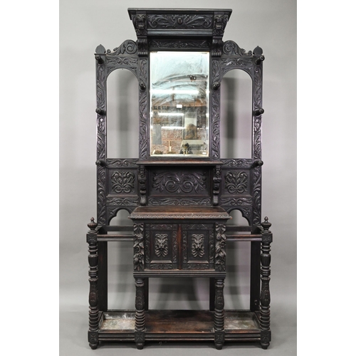 887 - A Victorian carved oak mirror backed hall stand, with cupboard and twin stick stands, 119 cm w x 39 ... 