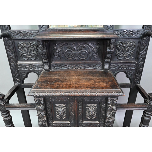 887 - A Victorian carved oak mirror backed hall stand, with cupboard and twin stick stands, 119 cm w x 39 ... 