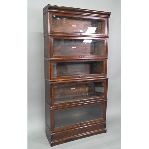 897 - A dark oak five section Globe Wernicke library bookcase, with glazed-in hinge-over doors, on a plint... 