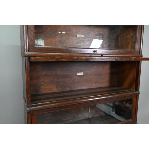 897 - A dark oak five section Globe Wernicke library bookcase, with glazed-in hinge-over doors, on a plint... 