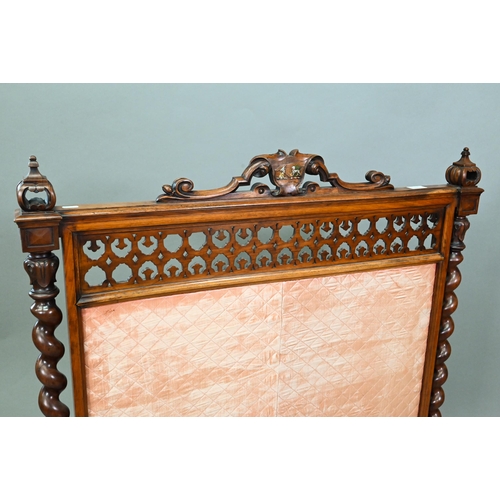 905 - A Victorian mahogany framed fire screen with polychrome armorial device to the crest rail, over a fa... 