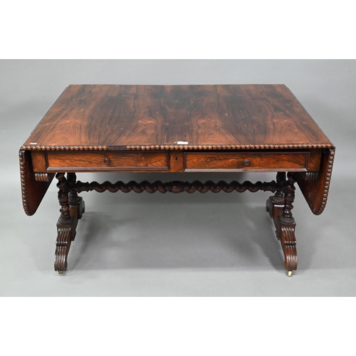 922 - A Regency rosewood sofa/library table, the rectangular top with beaded edge and rounded drop leaf en... 