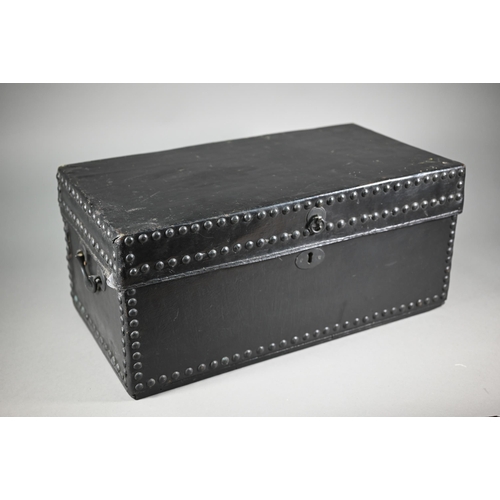 938 - An antique studded black clad leather trunk, with carrying handle to each side, 57 cm x 30cm x 26 cm... 