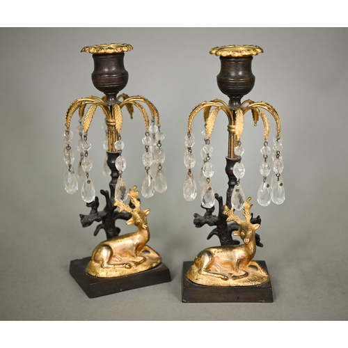 1166 - A pair of Empire period bronze and gilt candlesticks, with palm-fronds suspended with glass bead dro... 