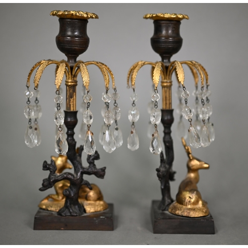 1166 - A pair of Empire period bronze and gilt candlesticks, with palm-fronds suspended with glass bead dro... 