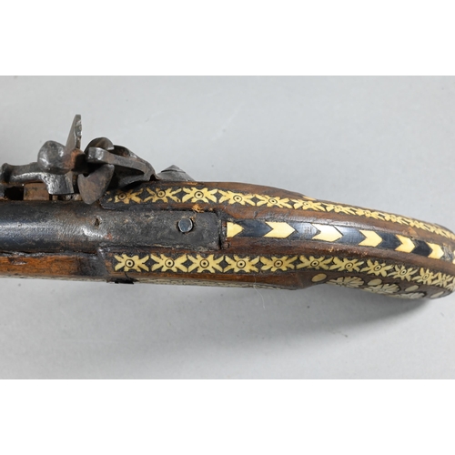 1068 - An Indo-Persian flintlock pistol with 25 cm barrel, the walnut fullstock richly inlaid with bone and... 