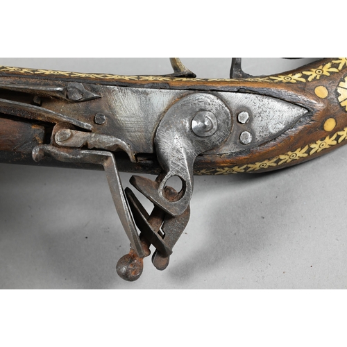 1068 - An Indo-Persian flintlock pistol with 25 cm barrel, the walnut fullstock richly inlaid with bone and... 