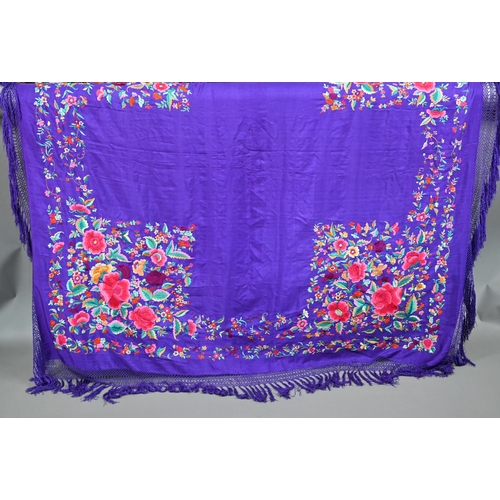 1124 - A circa 1930s Chinese silk 'piano' shawl, the purple ground profusely decorated with flowers in colo... 